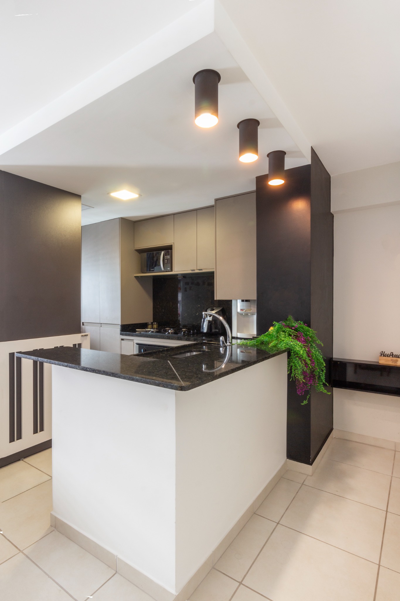 Cozinha integrada com iluminação direcionada e apoio para refeições