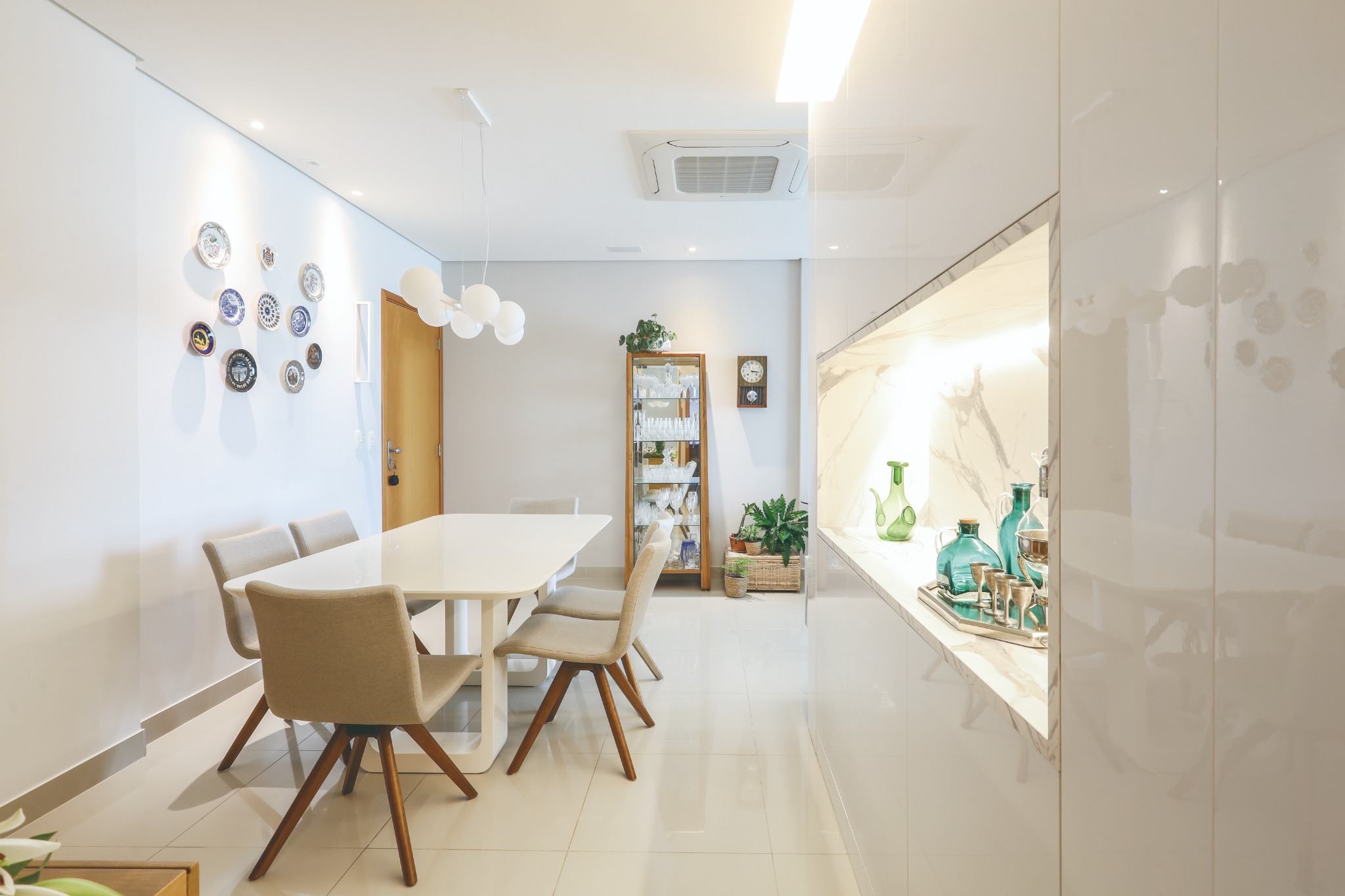 Sala de jantar com marcenaria, iluminação e peças pessoais